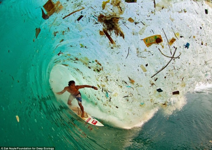 27. Un surfista cavalca un onda piena di immondizia, in Indonesia