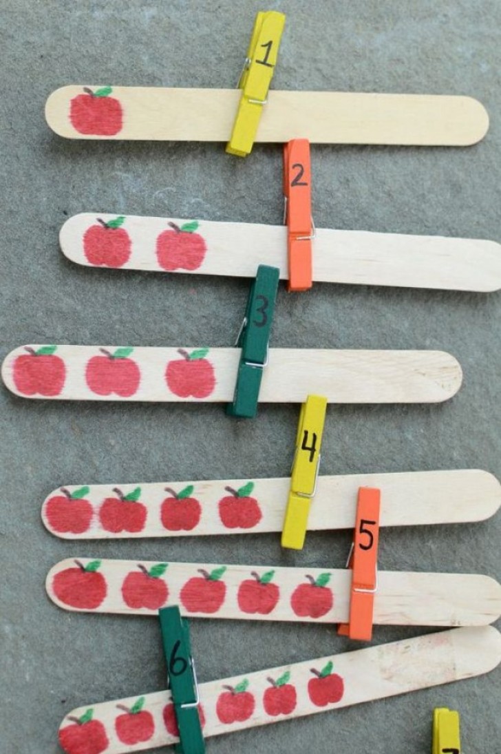 Sui bastoncini dei gelati disegnate delle mele. Poi, su delle mollette, un numero. Il bambino dovrà agganciare la molletta numerata al bastoncino corretto.