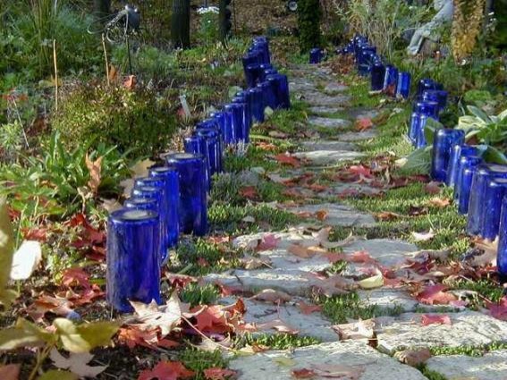 2-Para delinear un camino transitable y proteger los mazos de flores alrededor, planta en el terreno botellas en vidrio, posiblemete todos iguales.