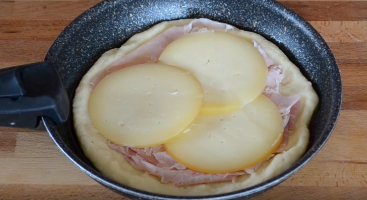 Verdeel de puree in twee delen en vorm twee schijven. Vet een pan in met olijfolie en plaats hier de eerste schijf puree in. Bekleed deze laag met ham en kaas en plaats de tweede schijf erover.
