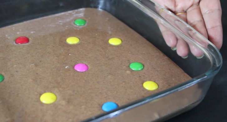 Pour the batter into the greased baking dish, and decorate it by putting some Smarties candy on the surface.