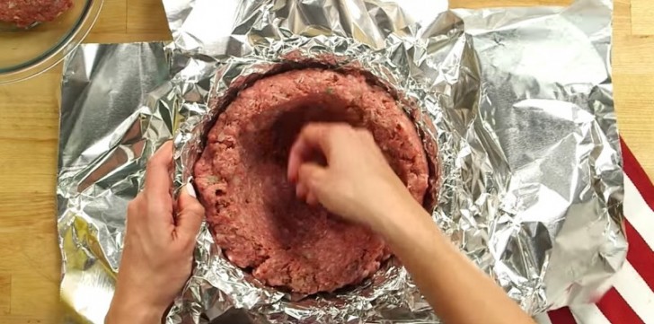 Täck en stor skål med aluminiumfolie, häll köttfärsen inuti och pressa den mot insidan så att ni får ett hål i mitten.