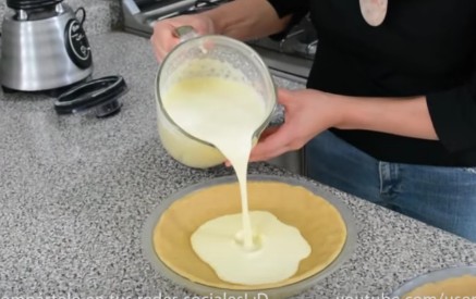 In un frullatore aggiungete il latte condensato e quello evaporato, il formaggio spalmabile, l'essenza di vaniglia e le uova. Frullate per 30 secondi, poi versate il liquido sulla pasta di biscotti.
