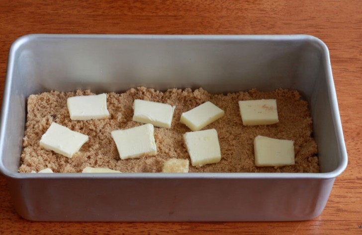 2. In una teglia rettangolare ponete 100 gr di zucchero di canna e cospargetelo con l'equivalente di 3 cucchiai di burro tagliato a cubetti.