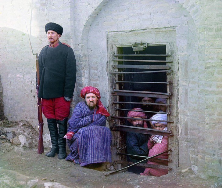 14. Gedetineerden die worden bewaakt door een Russische soldaat kijken door de tralies van de zindan de typische gevangenis voor die tijd in de Centraal-Aziatische regio - 1907-1915.