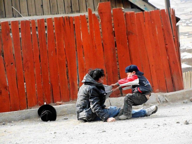 Un bambino cerca di soccorrere e far rialzare il padre alcolizzato, togliendolo da mezzo la strada.