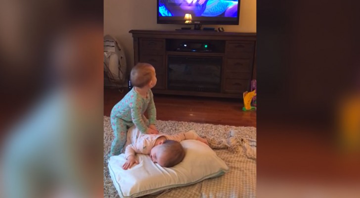 Tvillingarna tittar på TV, men det som gör att mamman filmar är något mycket roligare