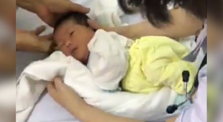 Een verpleegster laat haar methode zien om een pasgeboren baby in slaap te brengen met een handdoek en een groot badlaken
