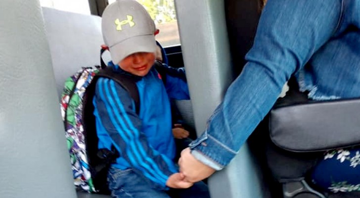 De schoolbuschauffeur houdt de hand van dit huilende kind vast op zijn eerste schooldag