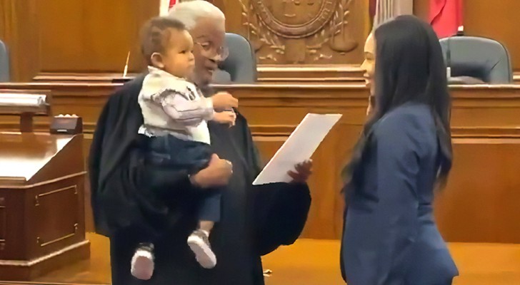 Der Richter hält das Baby einer jungen Mutter, während sie einen Eid ablegt, Anwältin zu werden