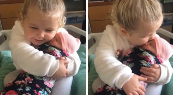 Das 3-jährige Mädchen hält ihre Schwester zum ersten Mal in den Armen und verliebt sich sofort in sie