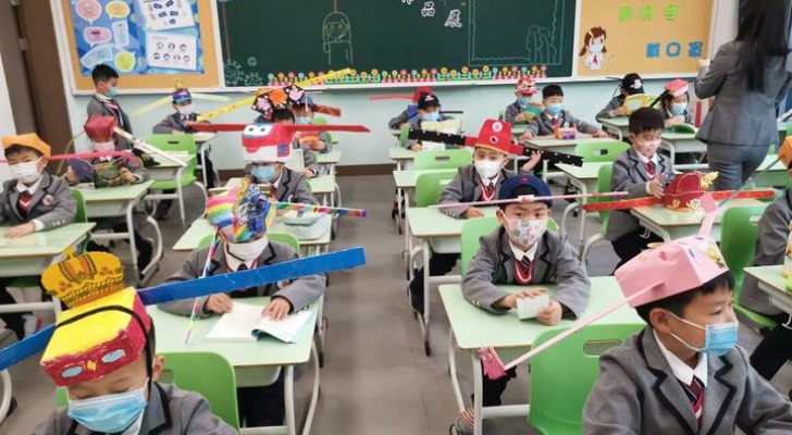 Cina: in questa scuola elementare, gli alunni indossano un cappello largo e colorato per mantenere la distanza di sicurezza