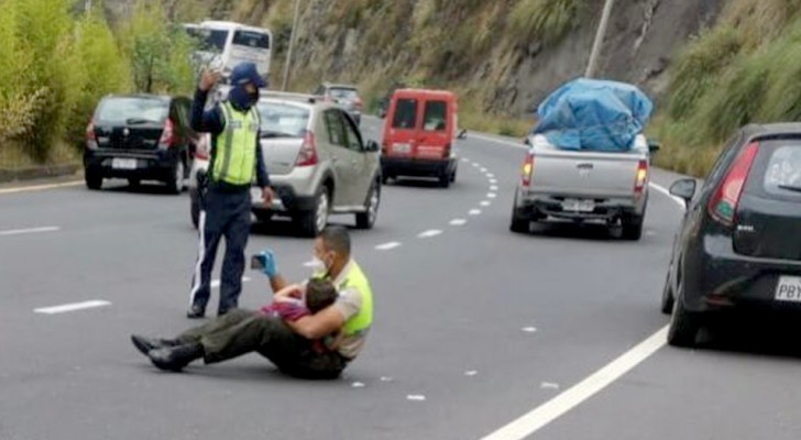 A policeman comforts a 4-year-old boy after a car accident by holding him tightly 