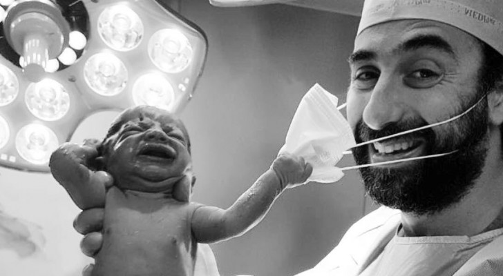 En nyfödd bebis drar bort munskyddet från sin läkare - en bild som redan blivit en stark symbol för år 2020