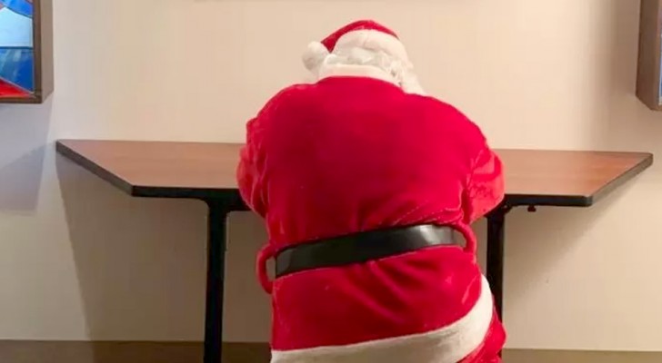 Un uomo vestito da Babbo Natale si inginocchia e prega per i bambini ricoverati in un ospedale pediatrico