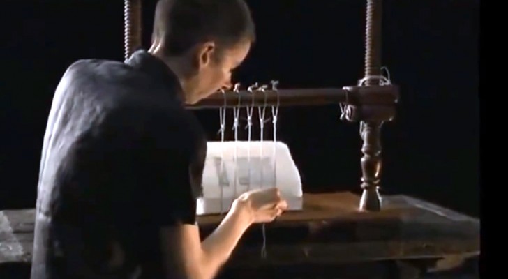 Een man naait vellen papier aan elkaar om een kwalitatief hoogwaardig product te creëren