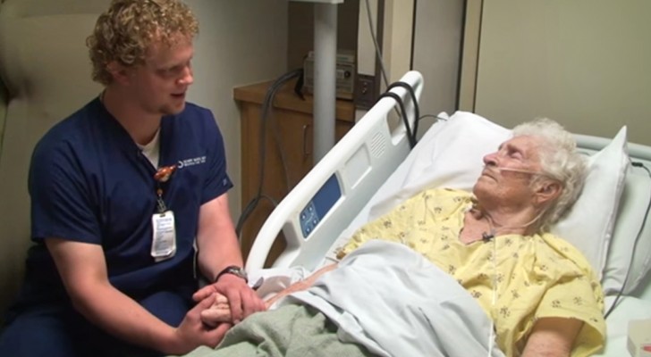Un infermiere si siede accanto a un'anziana paziente: ciò che fa la commuove nel profondo
