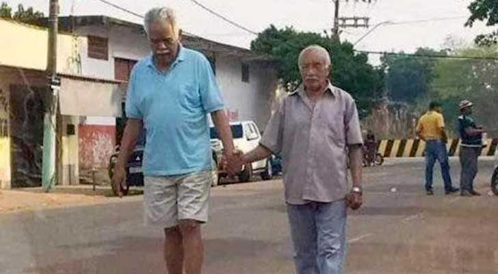 Two elderly people walk down the street holding hands - the image of true friendship