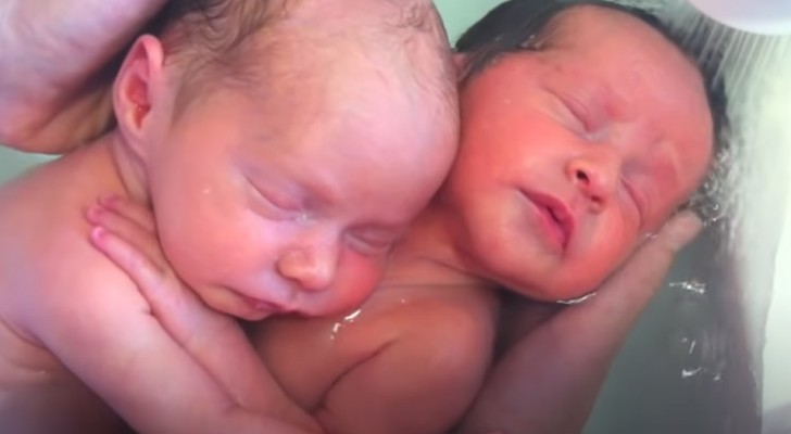Gemelos recién nacidos se abrazan durante el baño como si aún estuvieran en el vientre materno