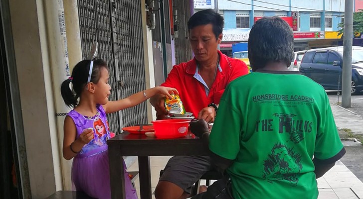 Ein Vater und seine Tochter laden einen hungrigen Obdachlosen zu sich an den Tisch ein