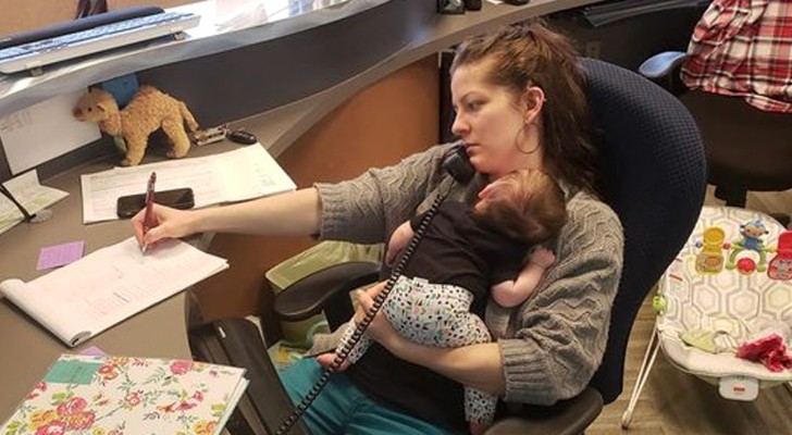 A mother works with her daughter in her arms, unaware that her boss is watching her