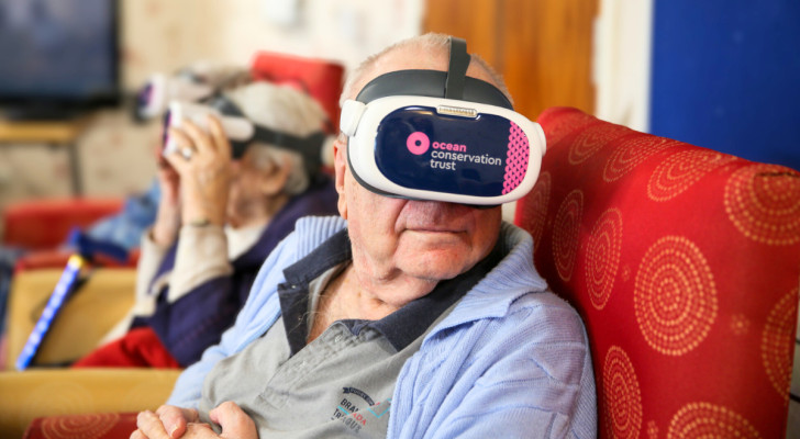 Een oudere man draagt een virtual reality headset om de oceaan te zien