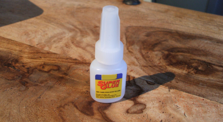 a bottle of superglue on a wooden shelf