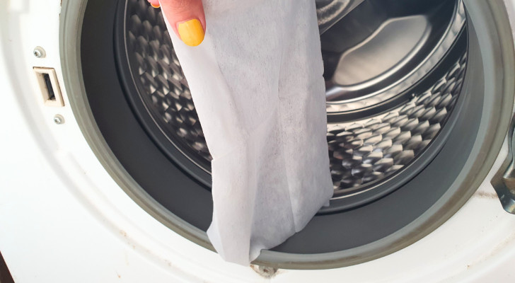 a fabric softener sheet held up in front of a dryer