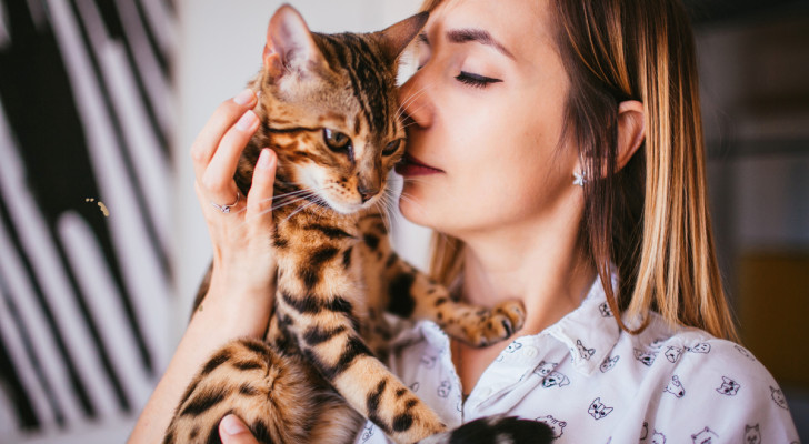 una donna coccola un gatto che tiene la testa vicino al suo viso