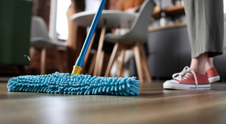 mensen die het huis schoonmaken met een mop op de voorgrond