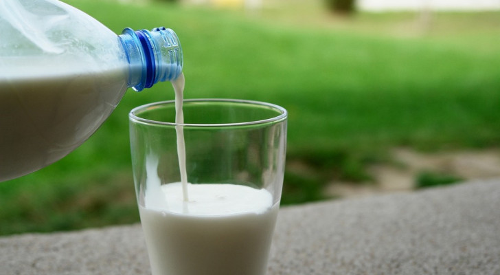 En person som häller upp mjölk i ett glas