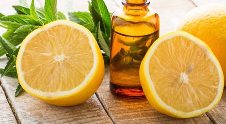 Una boccetta di olio essenziale in mezzo a due mezzi limoni