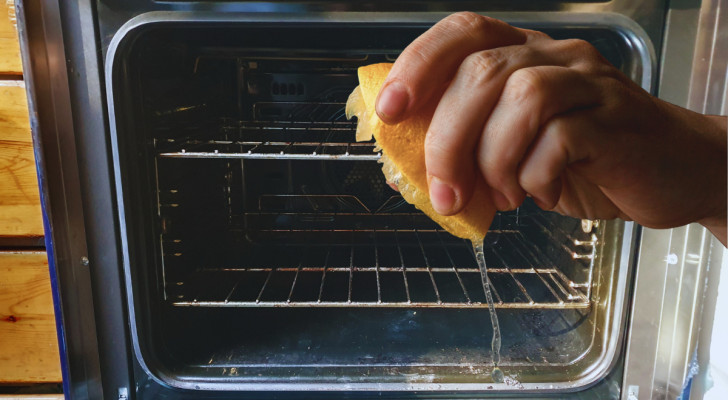 an open dirty oven in the background and a lemon being squeezed in the foreground