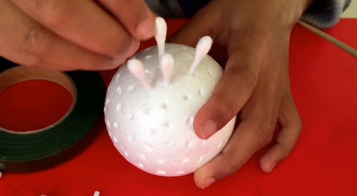 Er steckt Wattestäbchen in einen Ball aus Styropor: ein tolles Projekt, das man mit Kindern machen kann! 